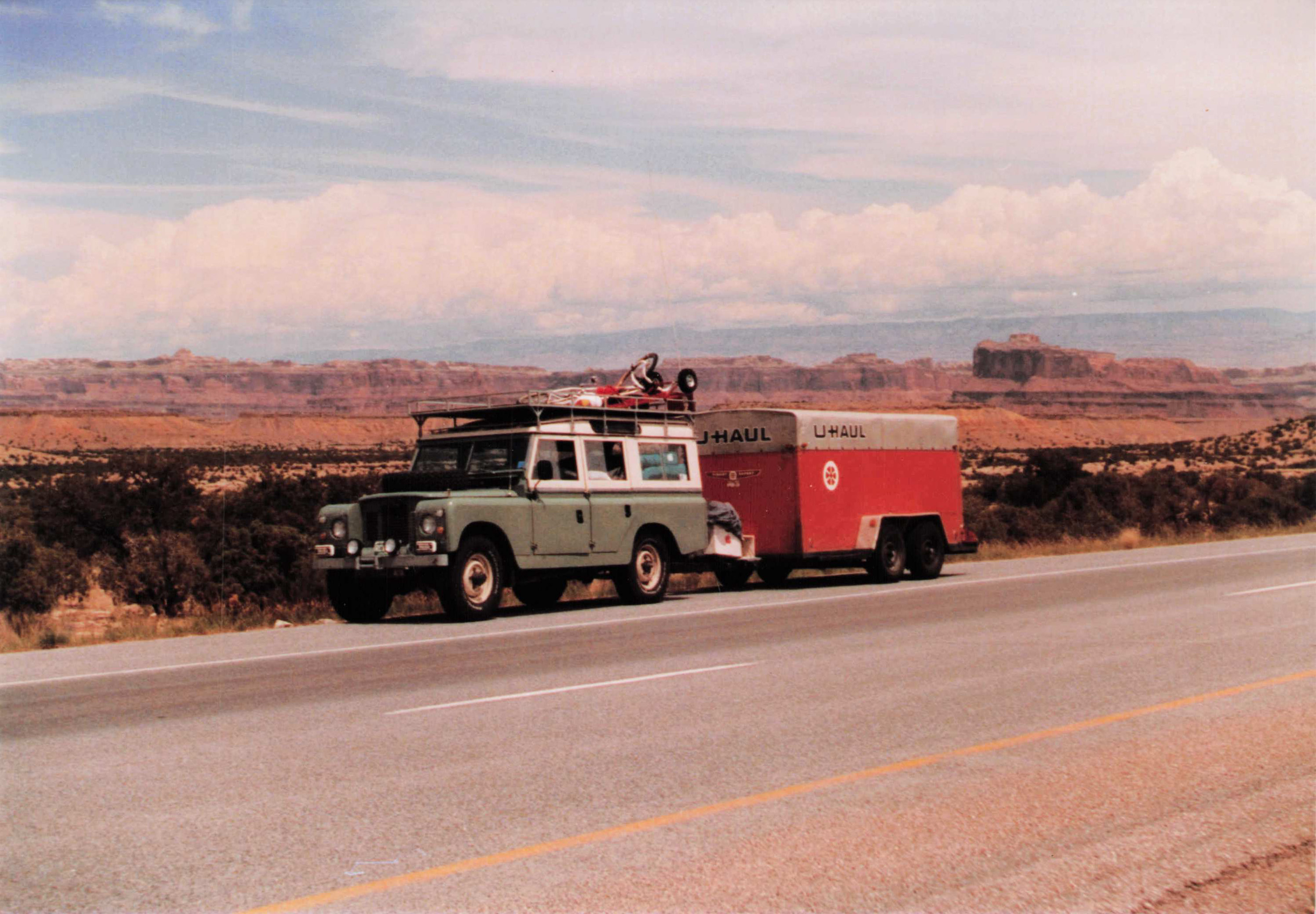 Land Rover + U-Haul driving through red rock canyon country, est. 1990