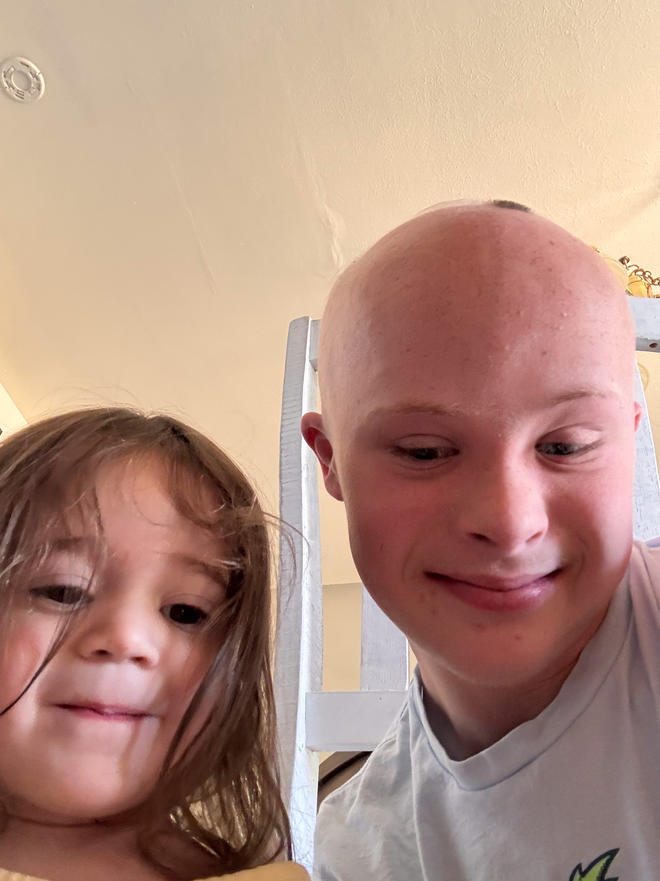Close selfie-angle shot of Dylan and a young child, both looking down, indoor setting.