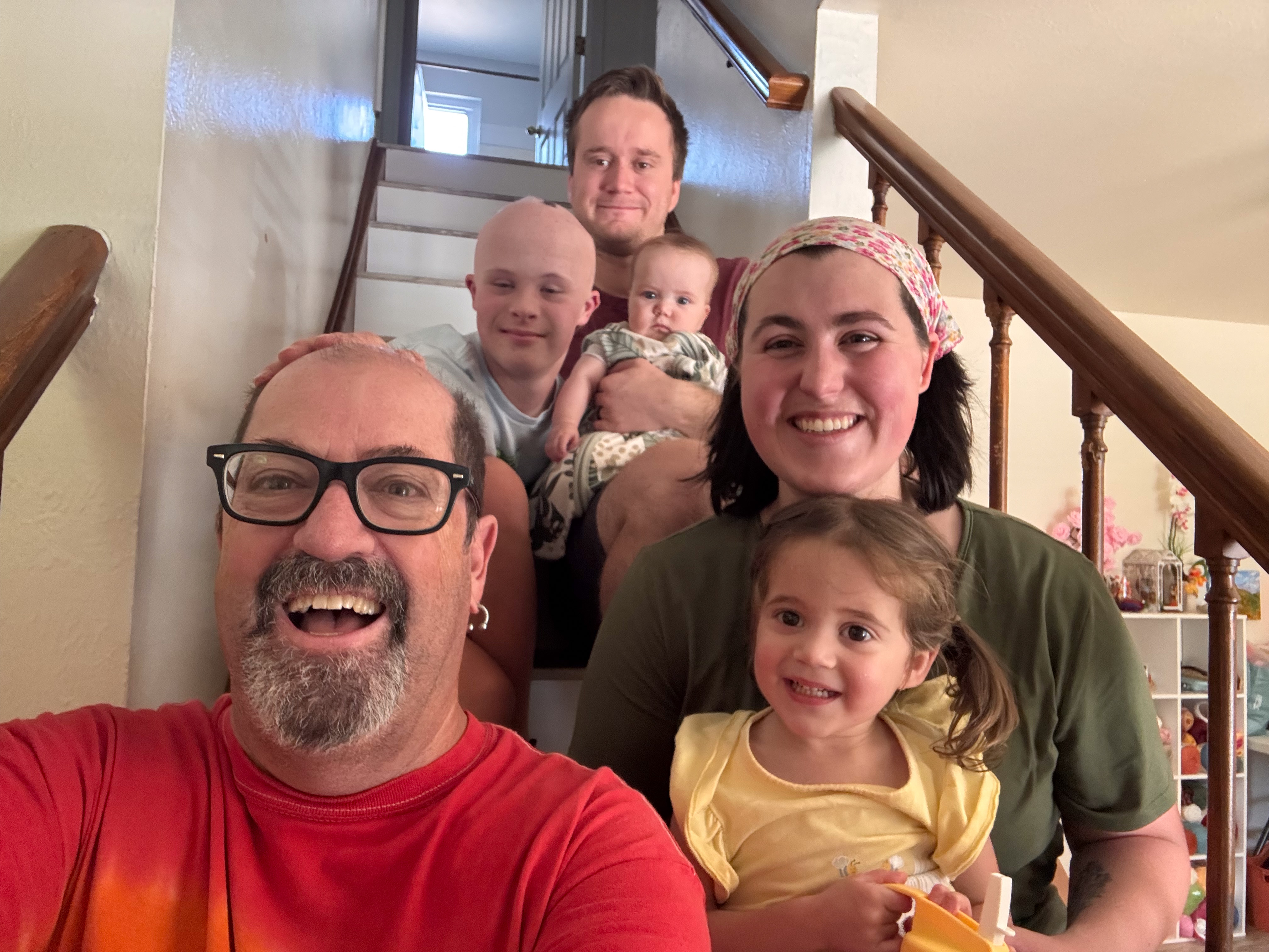 Group photo on an interior staircase — six people including Dylan and Ivy, arranged for depth along the stairs, everyone smiling.