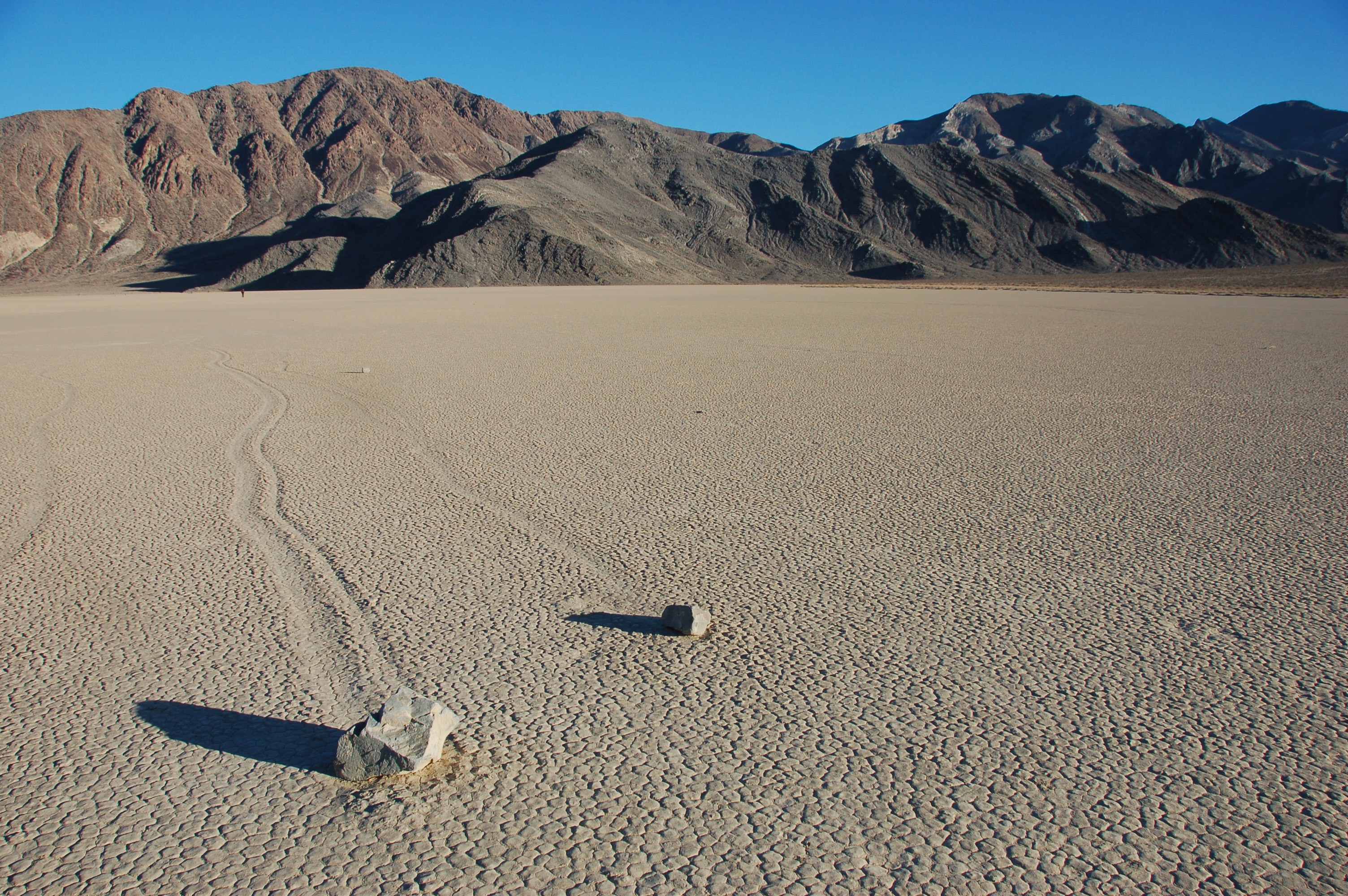 A sailing stone and its long track across the cracked mud of Racetrack Playa, Panamint Range behind — Death Valley, 2012-11-23.