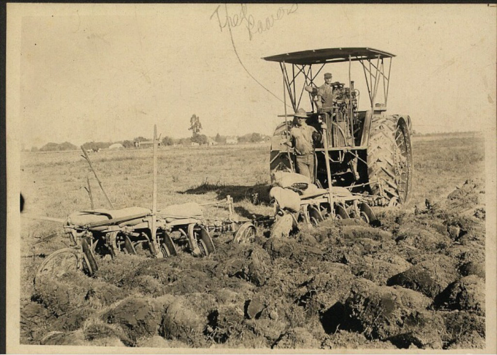 Fred Laurence Powers beside a huge tractor in a fresh-plowed field — a tractor like this one would kill him in 1913. "Fred Powers" penciled at the top.