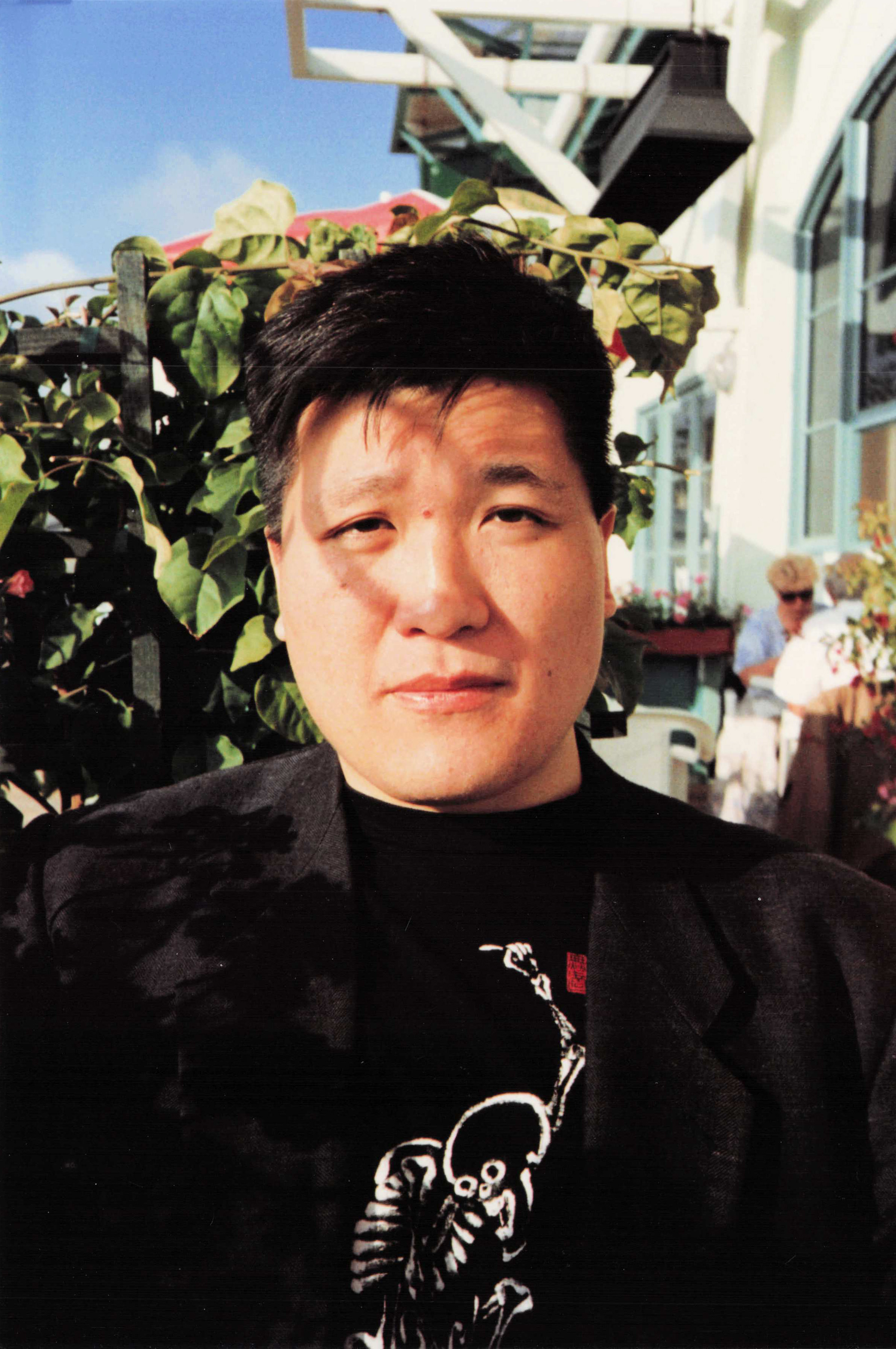 Minsoo Kang at a restaurant in LA — black blazer, skeleton-print shirt. Early 1990s.