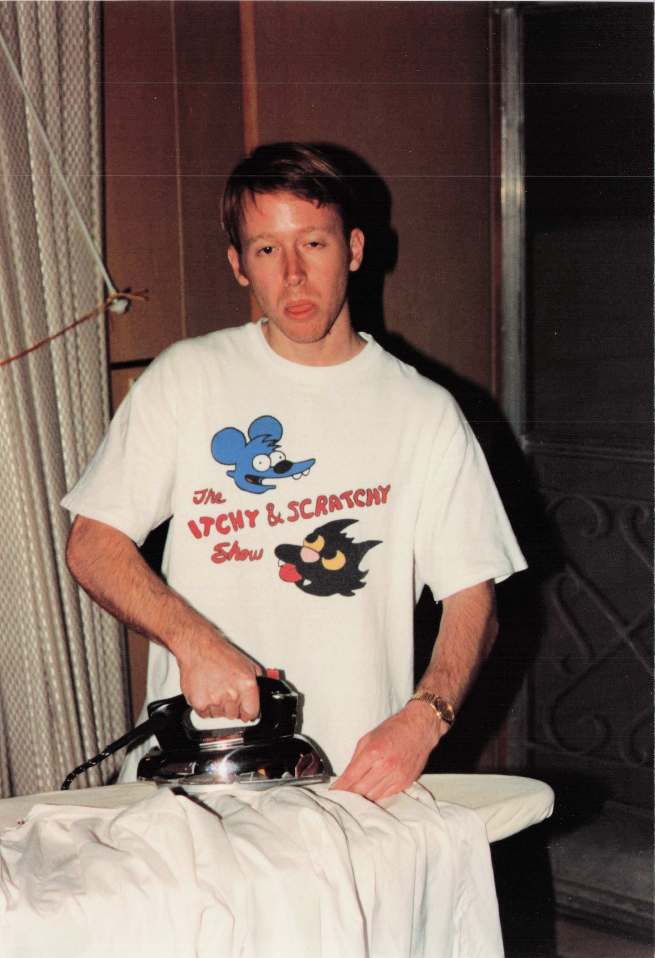 Jay Fisher in an "Itchy & Scratchy" t-shirt, ironing a shirt