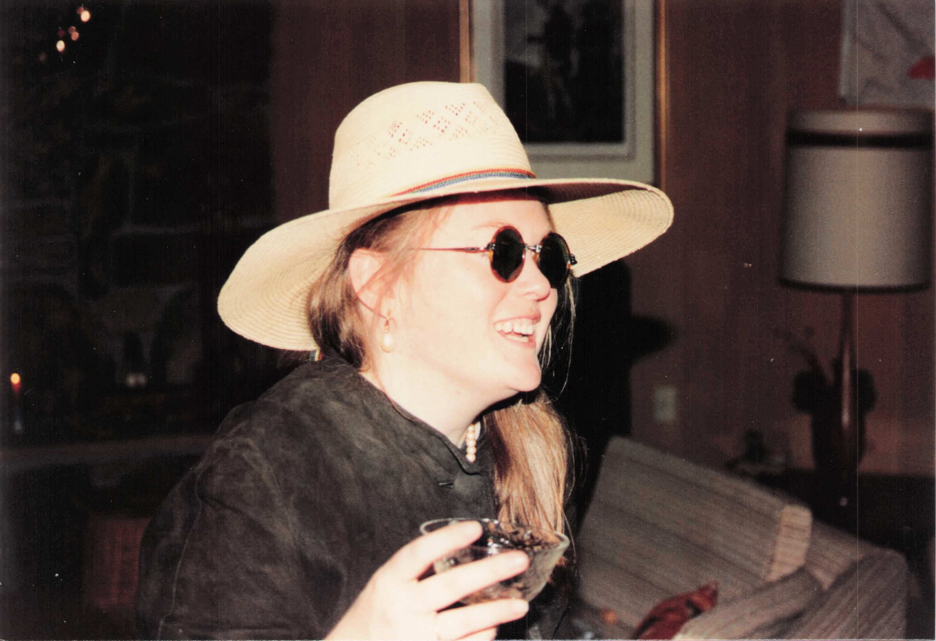 Rebecca Casey in a straw hat and sunglasses, laughing
