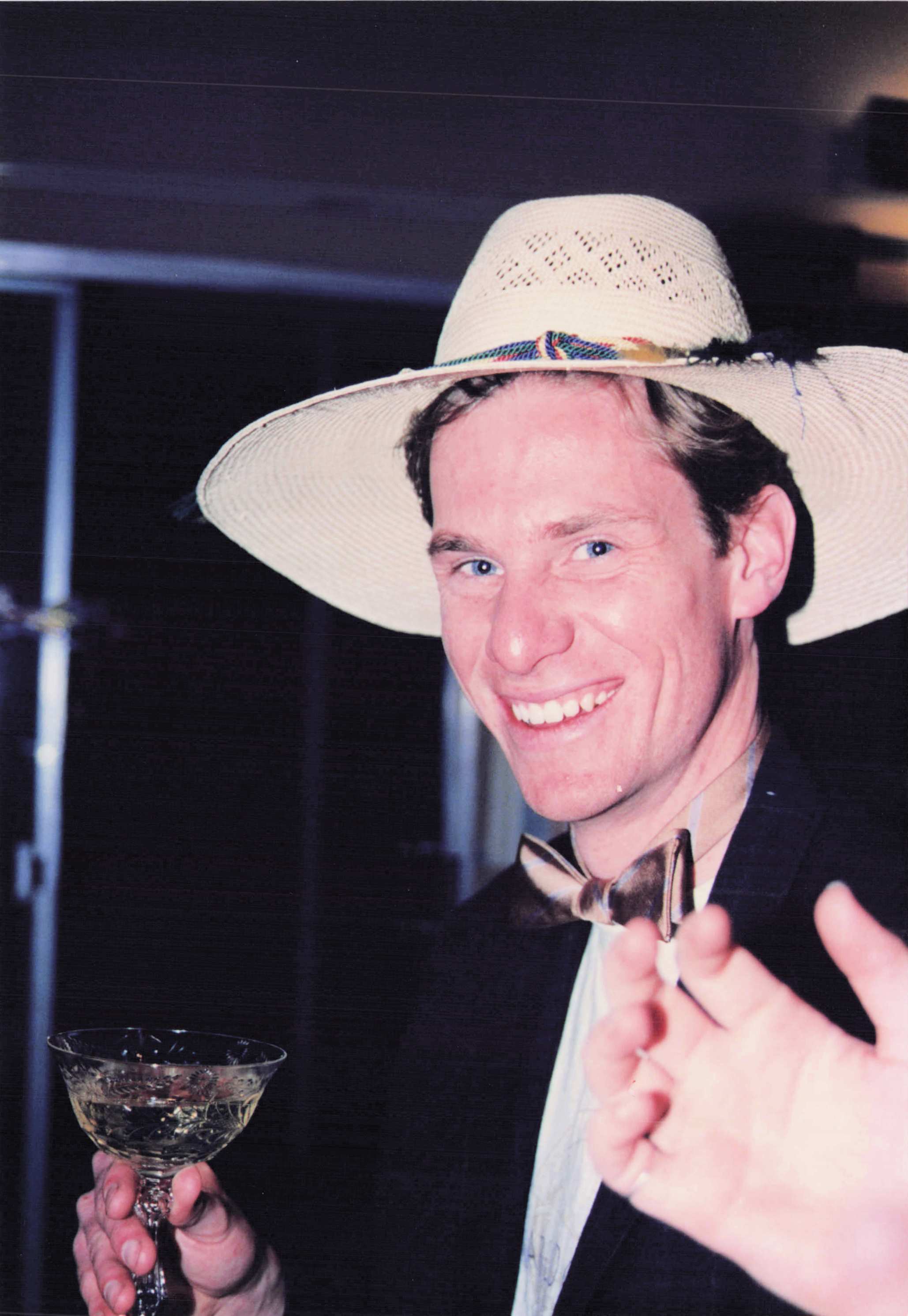 Mike Cunningham, also in the straw hat, toasting with a glass of champagne