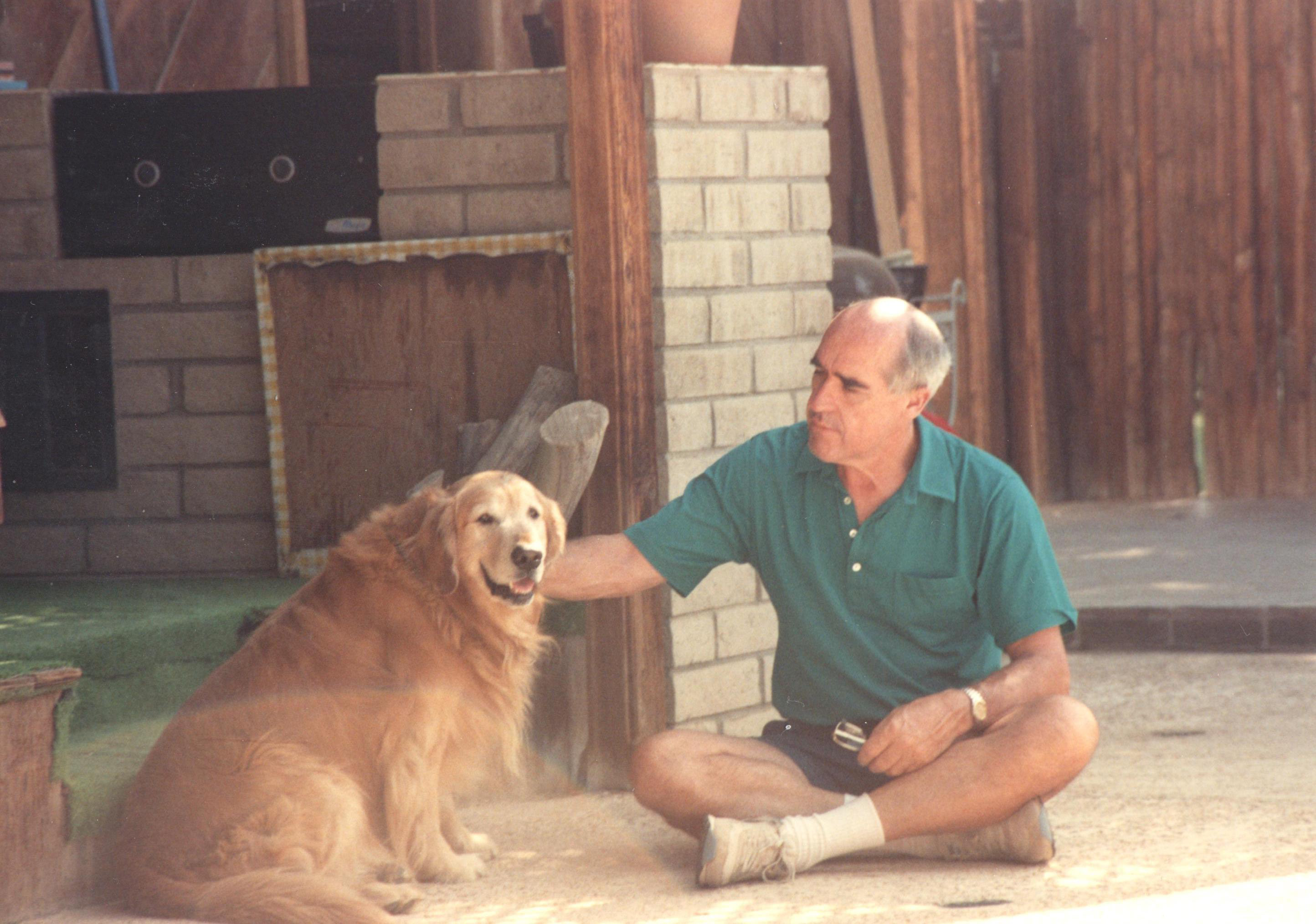 Phil sitting cross-legged with a golden retriever in the backyard, mid-to-late 1980s — he loved dogs
