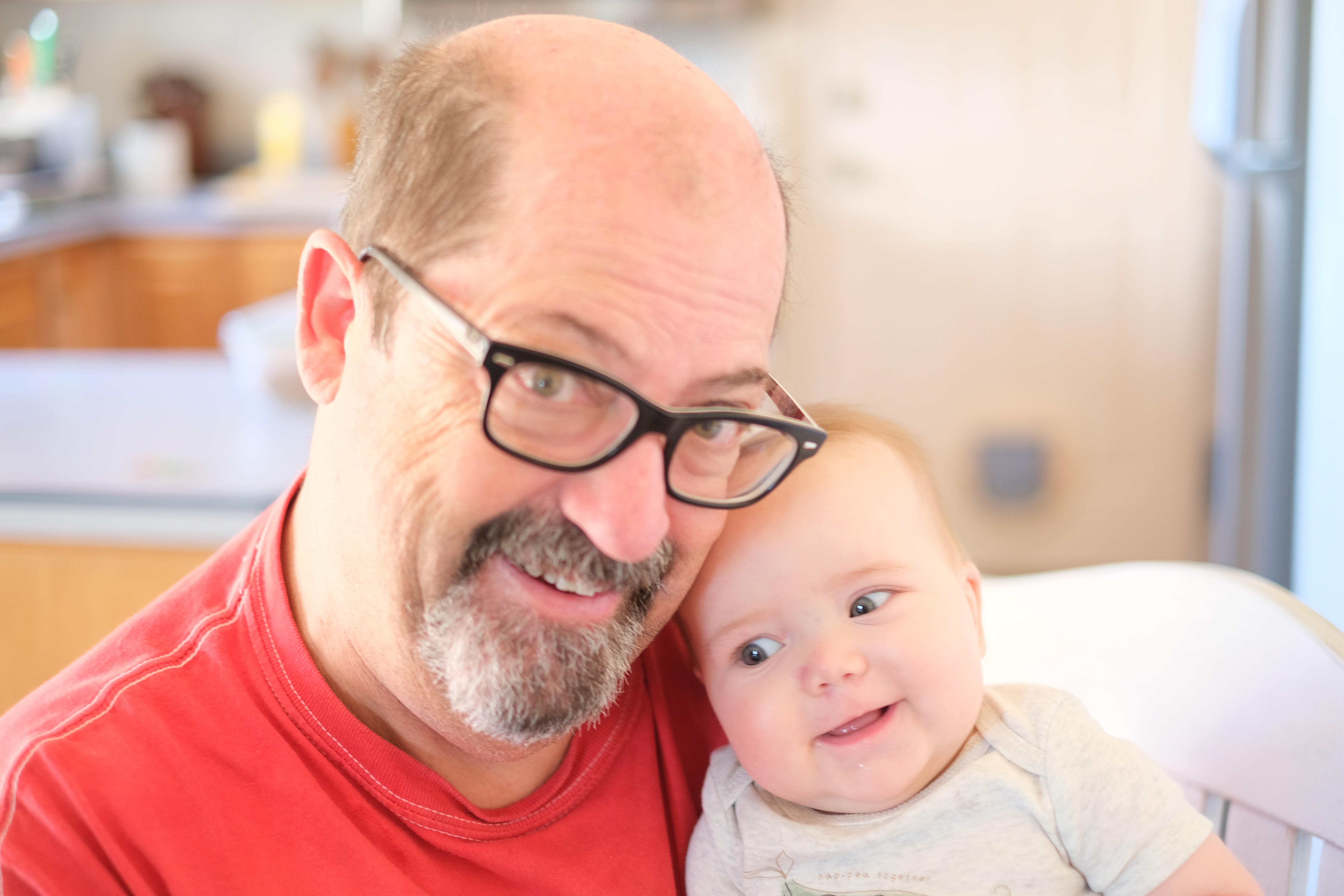 Close cheek-to-cheek portrait of Fred and Ivy, focus sharp on her face, soft-focus kitchen background.