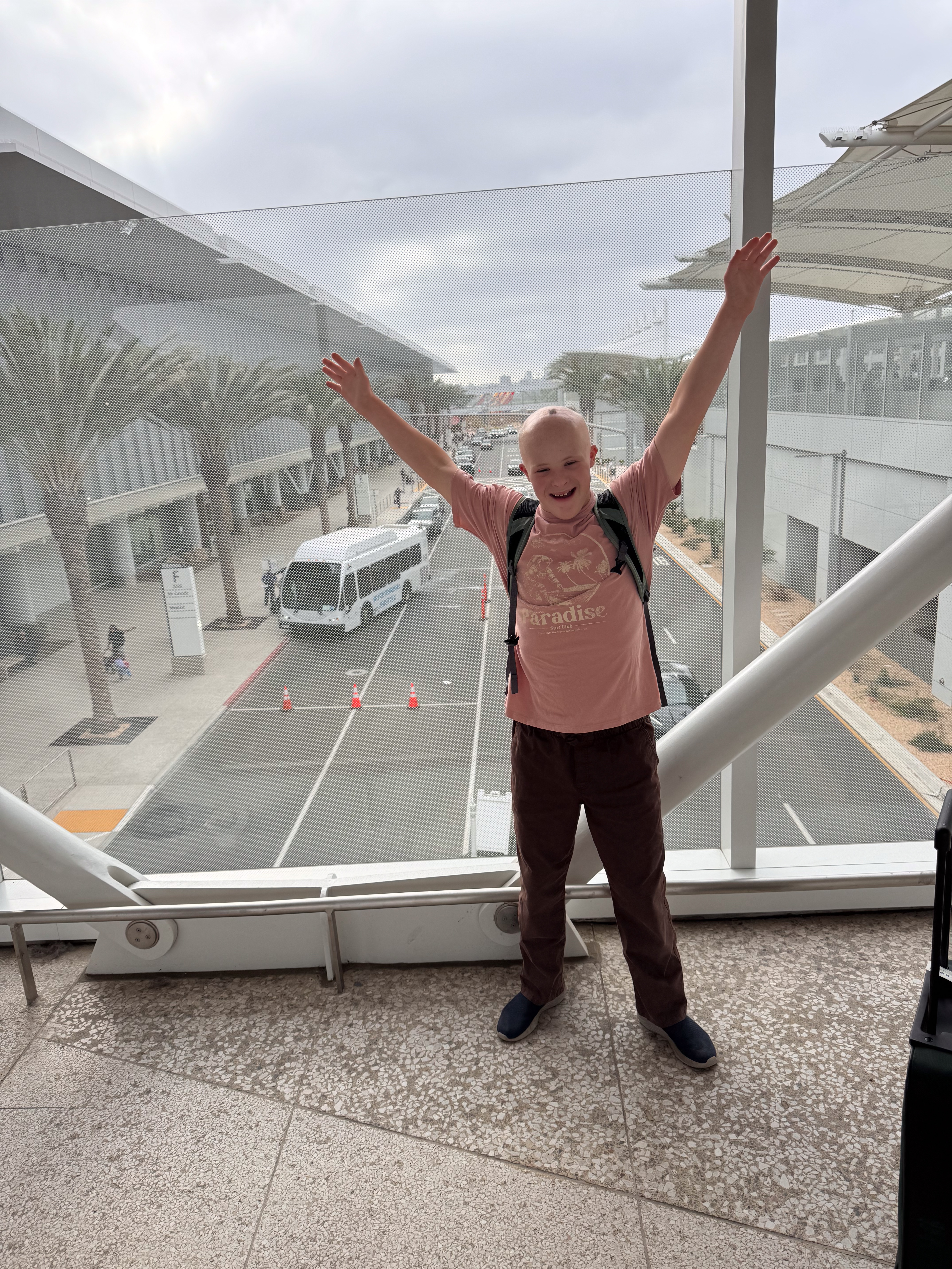 Dylan, arms raised, at the jet bridge window before the SAN–DEN flight.