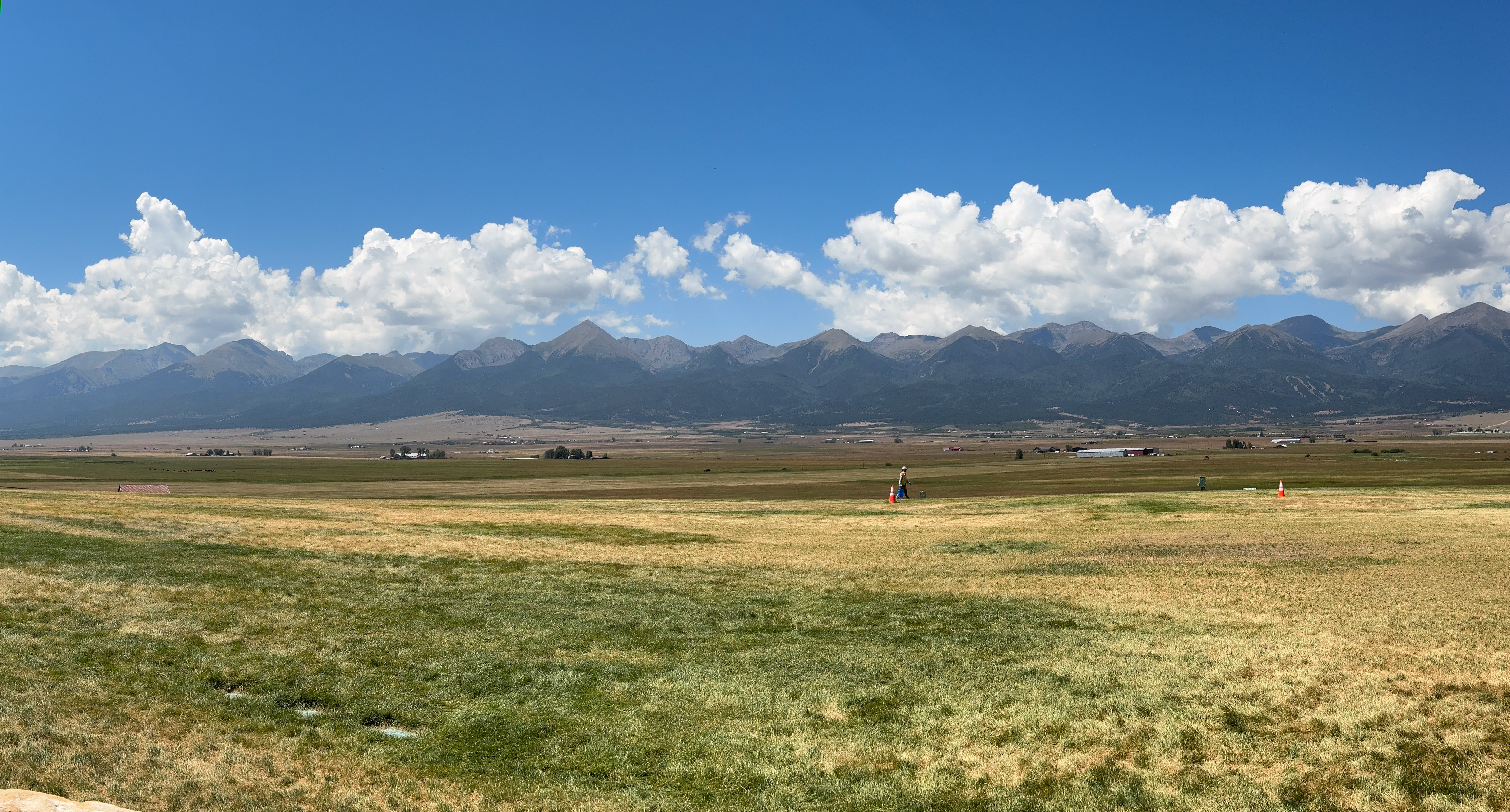 Panorama of a wide mountain valley under a big cloud sky.