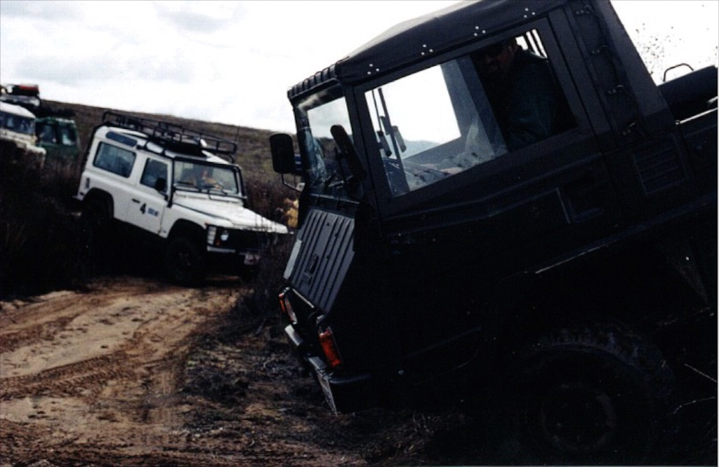 Low angle on a dirt road, white Land Rover in the background.