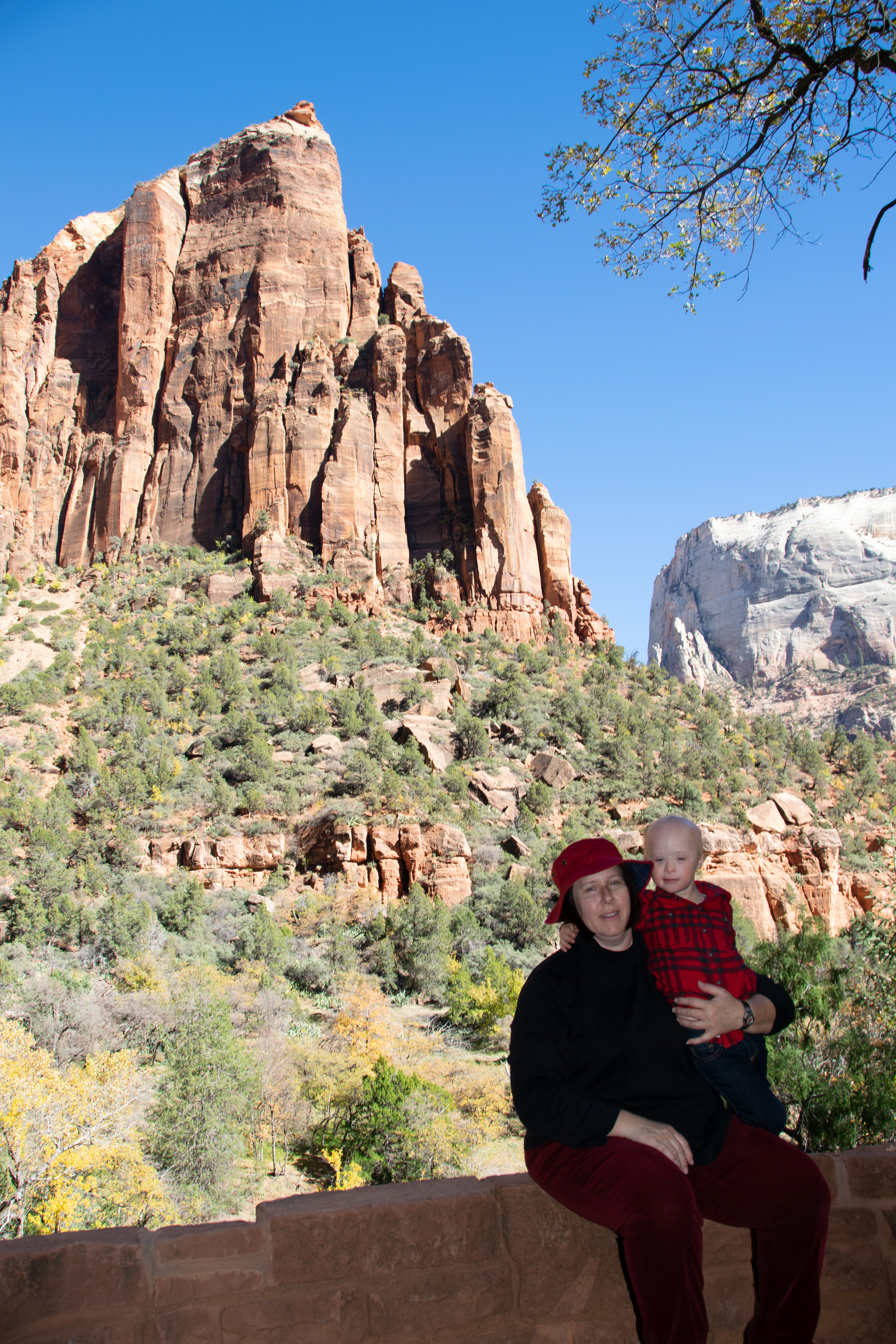 Becke holding Dylan in Zion, red sandstone behind