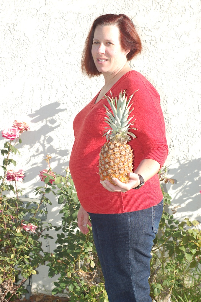 Becke, pregnant, cradling a pineapple against her belly — 2014-01-03, six days before Dylan was born.