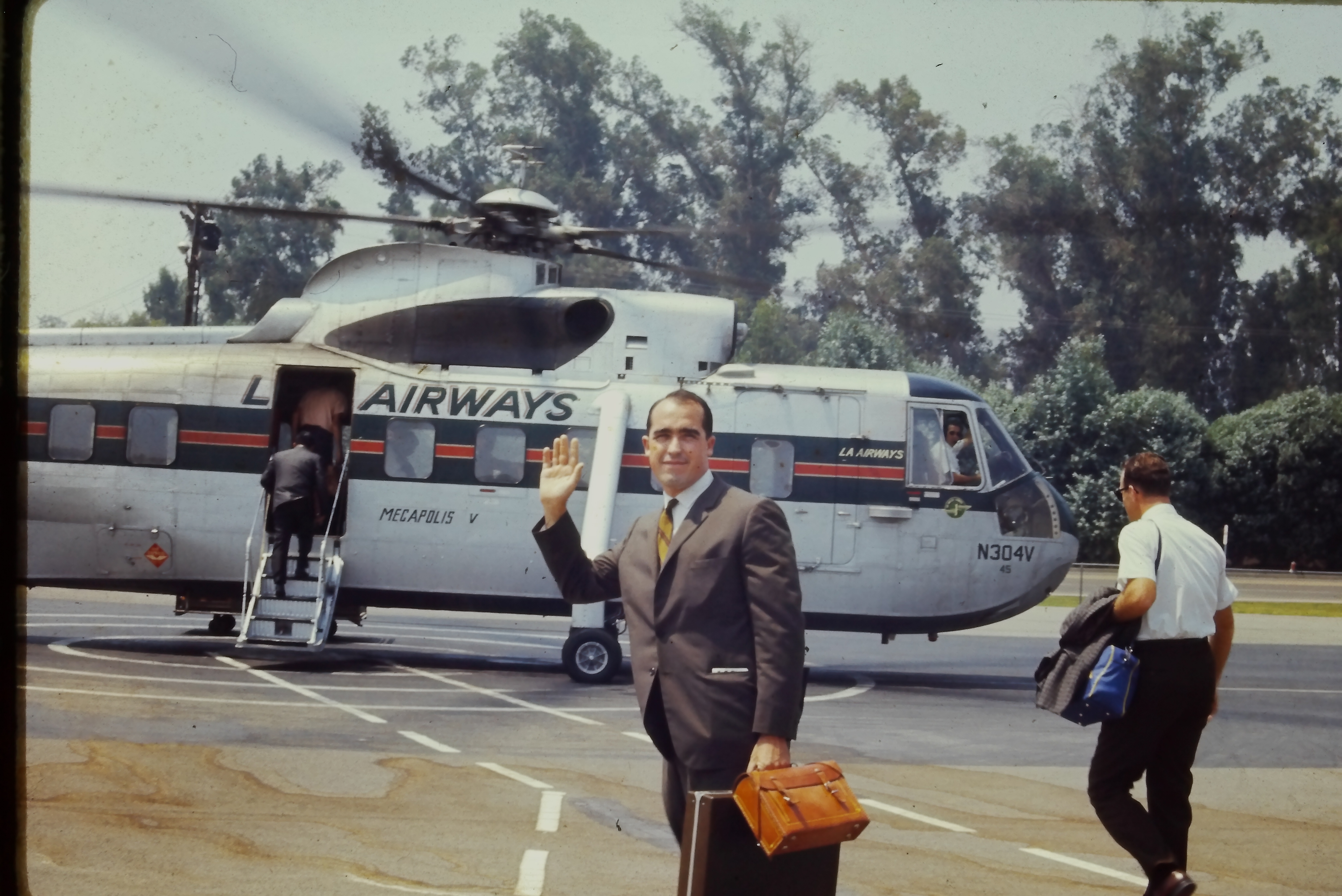 Young Phil in a suit, waving as he boards an LA Airways helicopter, est. 1966 — his Navy/early-career years